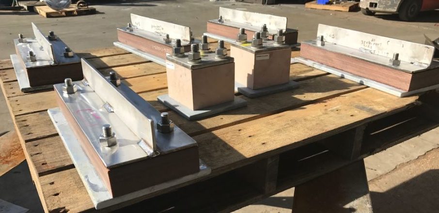 Piping shoes on a pallet outside, ready to be shipped with other pipe shoes and associated piping accessories.